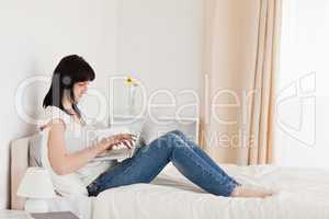 Good looking brunette woman relaxing with her laptop while sitti