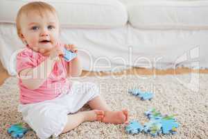 Cute blond baby playing with puzzle pieces while sitting on a ca
