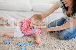 Lovely woman and her baby playing with puzzle pieces while sitti