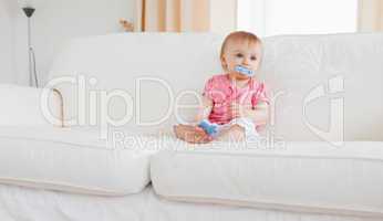 Lovely blond baby playing with puzzle pieces while sitting on a