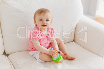 Baby playing with a ball while sitting on a sofa