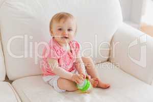 Baby playing with a ball while sitting on a sofa