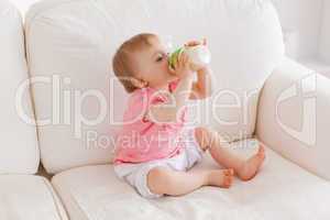 Baby bottle-feeding while sitting on a sofa