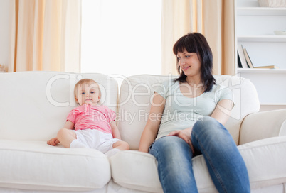 Pretty woman looking at her baby while sitting on a sofa