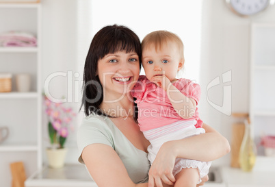 Beautiful woman holding her baby in her arms while standing