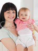 Good loooking woman holding her baby in her arms while standing