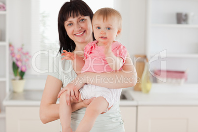 Charming woman holding her baby in her arms while standing