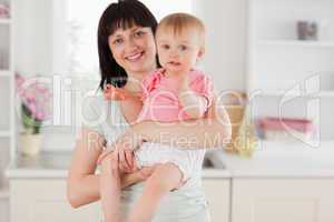 Charming woman holding her baby in her arms while standing
