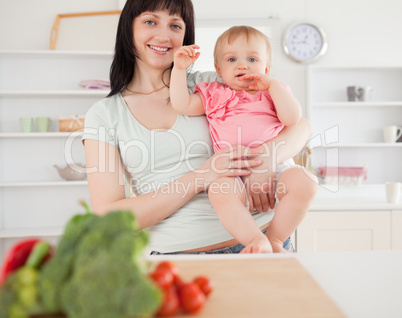 Lovely woman holding her baby in her arms while standing