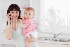 Beautiful woman on the phone while holding her baby in her arms