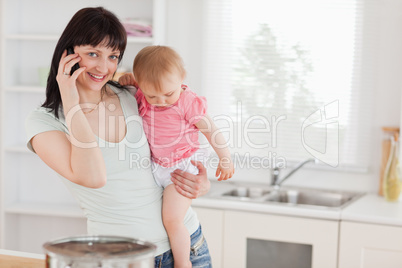 Attractive woman on the phone while holding her baby in her arms