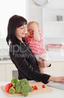 Good looking brunette woman in suit holding her baby in her arms