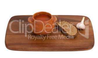Soup in clay pot on wooden kitchen board