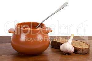 Borsch in clay pot on wooden table