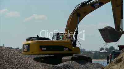 Yellow excavator loading gravel