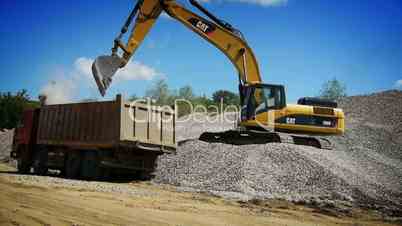 Yellow excavator loading gravel