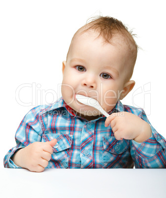 Cute little boy is biting spoon