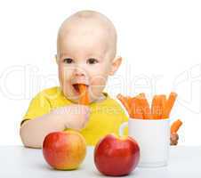 Cute little boy eats carrot and apples