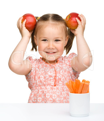 Cute little girl eats carrot and apples