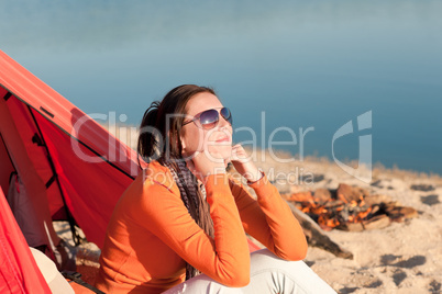 Camping happy woman sitting by campfire relaxing in tent