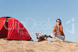 Camping happy woman sitting by campfire on beach