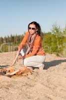 Camping happy woman making campfire on beach