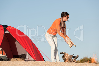Camping happy woman making campfire on beach