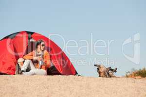 Camping happy woman sitting outside beach tent