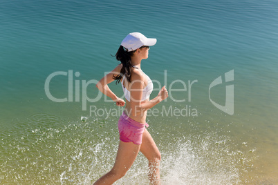Summer sport fit woman jogging along seashore