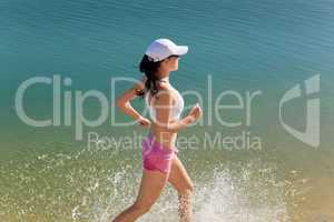 Summer sport fit woman jogging along seashore