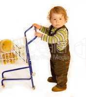 Kleinkind schiebt Einkaufswagen mit Kuscheltier