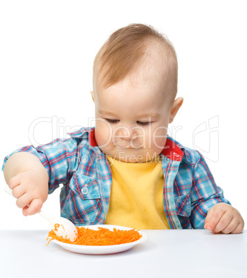 Cute little boy is playing with carrot salad