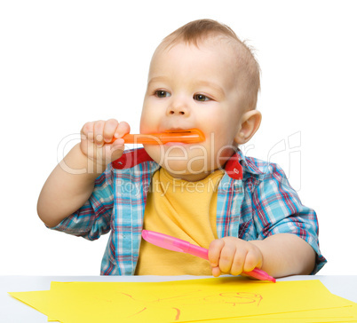 Happy little boy is playing with colorful markers