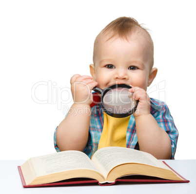 Little child play with book and magnifier