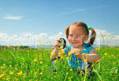 Little girl examining flowers using magnifier