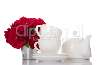 White crockery for tea and a bouquet of roses