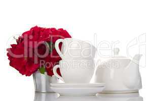 White crockery for tea and a bouquet of roses