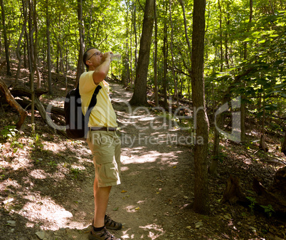 Senior man hiking in forest with backpack