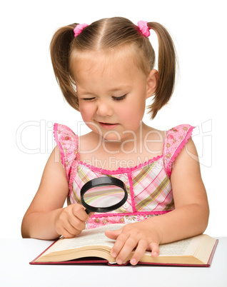 Little girl play with book and magnifier
