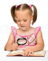 Little girl play with book and magnifier