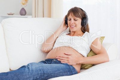 Smiling pregnant woman listening to music