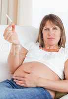 Gorgeous pregnant woman holding a cigarette while lying on a sof