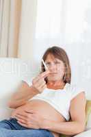Good looking pregnant woman holding a cigarette while lying on a