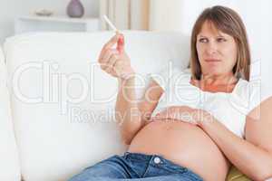 Beautiful pregnant woman holding a cigarette while lying on a so
