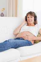Portrait of a smiling pregnant woman listening to music