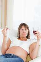 Beautiful pregnant woman holding a cigarette and a glass of red