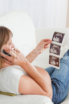 Beautiful pregnant woman on the phone and looking at an ultrasou
