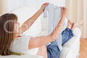 Good looking pregnant woman looking at a baby grow while lying o