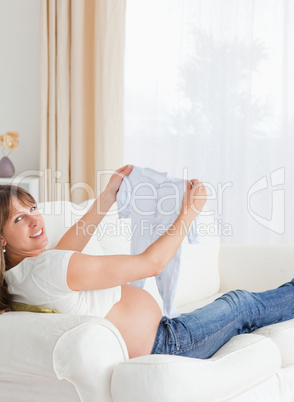 Lovely pregnant woman holding a baby grow and posing while lying