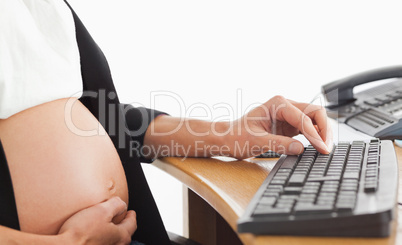 Pregnant woman on the phone working with a computer